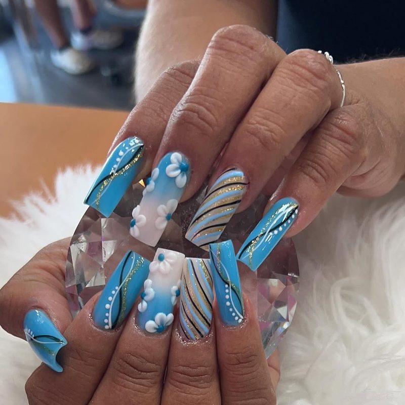 Blue floral nail art with gold accents